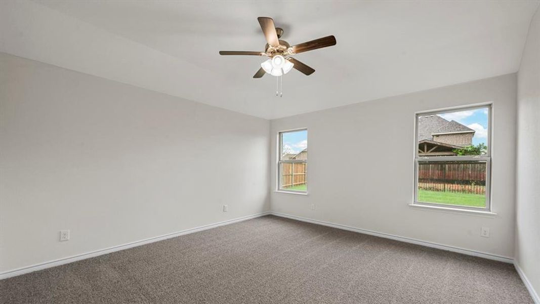 Carpeted room featuring light gray walls, two windows, and a ceiling fan with integrated lighting