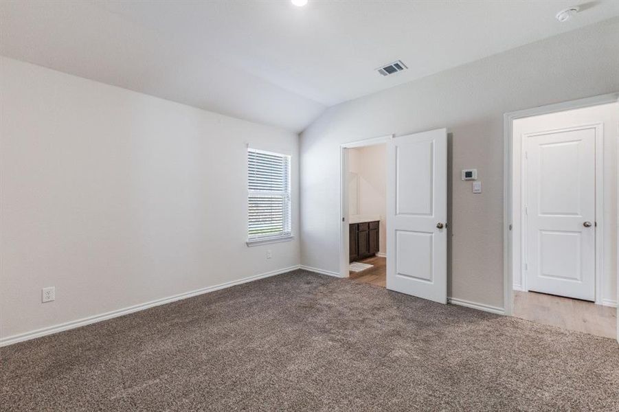 Unfurnished bedroom with vaulted ceiling, connected bathroom, and carpet Unfurnished bedroom with vaulted ceiling, connected bathroom, and carpet