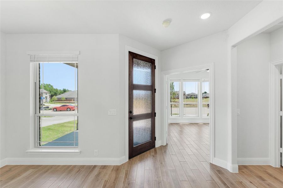 Home entryway with dark wood front door with glass panels, light hardwood floors, and white walls Home entryway with dark wood front door with glass panels, light hardwood floors, and white walls