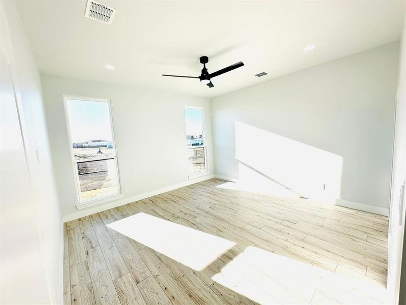 Empty room with ceiling fan and light hardwood / wood-style floors