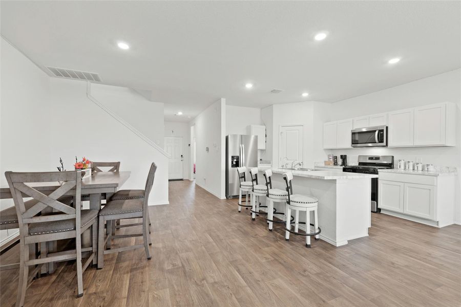 Enjoy the ultimate open-concept layout where the sleek kitchen and spacious dining area meet, featuring gorgeous wood-style flooring and bright recessed lighting that keeps the energy high throughout the day.