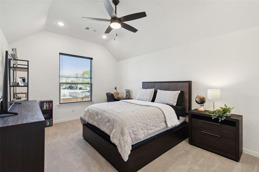 Carpeted bedroom with ceiling fan and vaulted ceiling