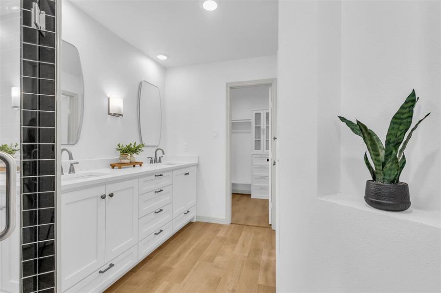 Bathroom with double vanity, light wood finished floors, recessed lighting, and a walk in closet Bathroom with double vanity, light wood finished floors, recessed lighting, and a walk in closet