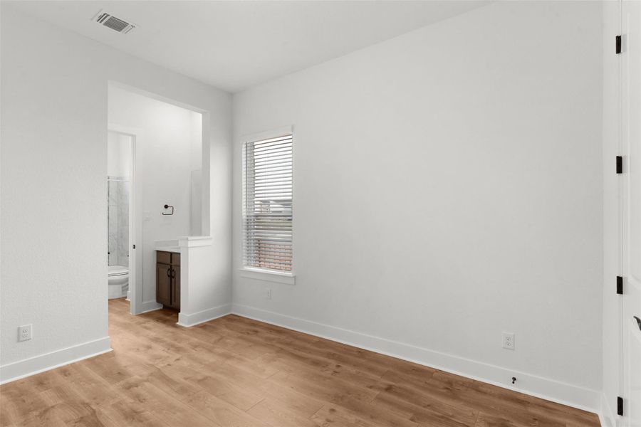Unfurnished bedroom with light wood finished floors and connected bathroom