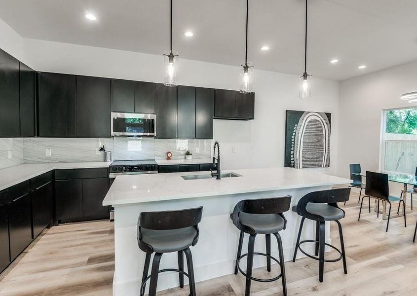 Kitchen with stainless steel appliances, sink, pendant lighting, backsplash, and light hardwood / wood-style floors