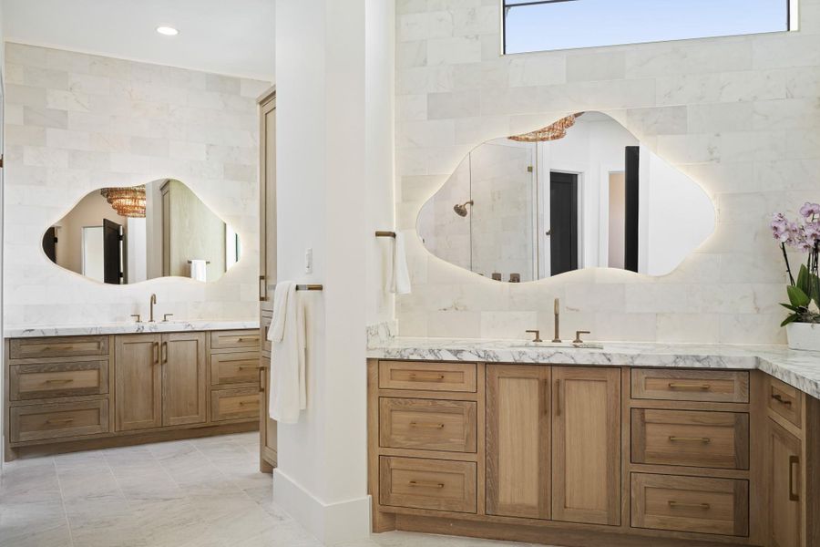 Upon entry to the primary spa bathroom, you are greeted by custom, made on site white oak cabinetry, art deco LED mirors, an incredible chandelier and floor to ceiling marble throughout.