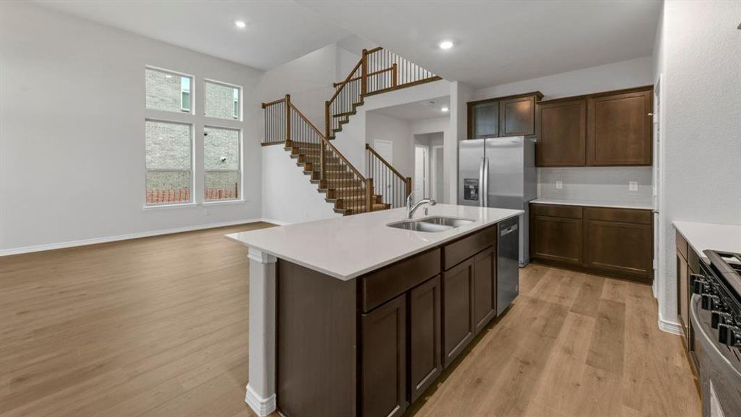 Kitchen featuring stainless steel appliances, an island with sink, dark wood finish cabinets, plenty of natural light, and recessed lighting Kitchen featuring stainless steel appliances, an island with sink, dark wood finish cabinets, plenty of natural light, and recessed lighting