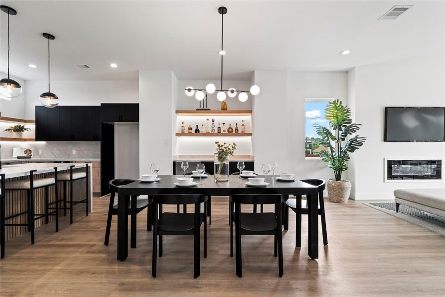 The dining area flows naturally into the kitchen and living room, featuring a built-in dry bar with floating shelves and a beverage cooler, perfect for entertaining. The dining area flows naturally into the kitchen and living room, featuring a built-in dry bar with floating shelves and a beverage cooler, perfect for entertaining.
