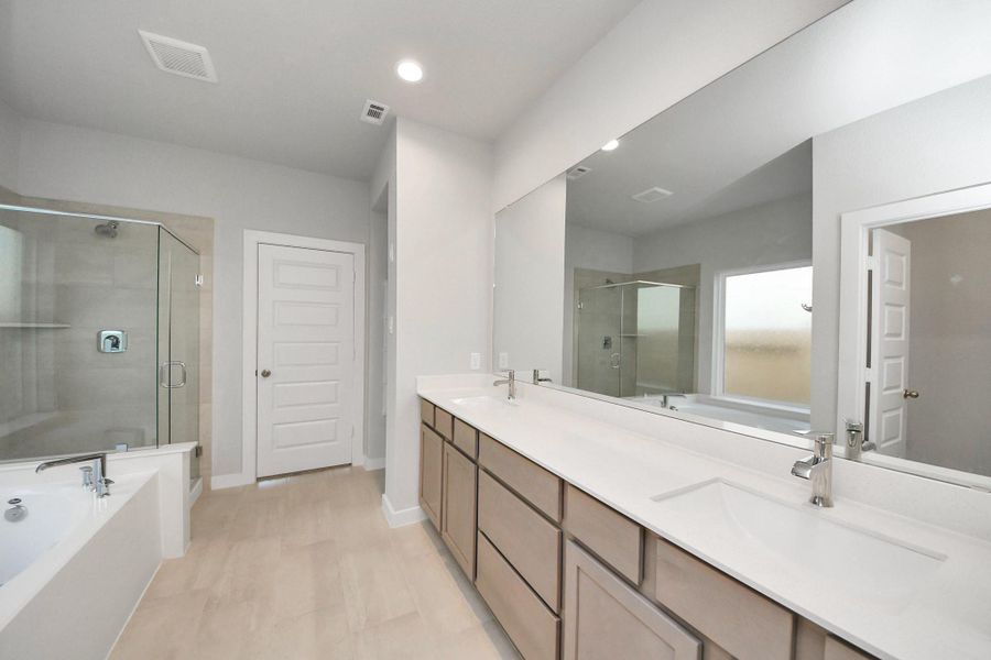 Elevate your daily routine at the elegant vanity, now equipped with double sinks, light countertops, modern hardware, and beautiful recessed lights. Sample photo of completed home with similar floor plan. Actual colors and selections may vary.