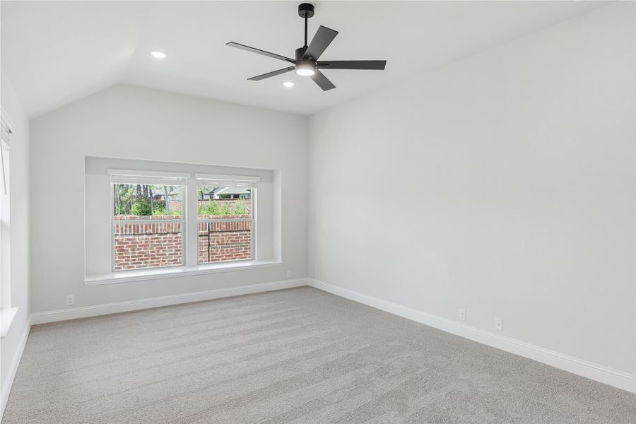 Empty bedroom with vaulted ceiling, black ceiling fan, carpet flooring, and a double window