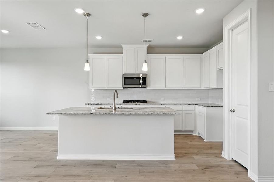 Kitchen with backsplash, light stone countertops, white cabinets, and recessed lighting Kitchen with backsplash, light stone countertops, white cabinets, and recessed lighting