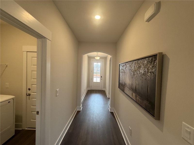 A well-lit hallway with rich flooring leads to a b