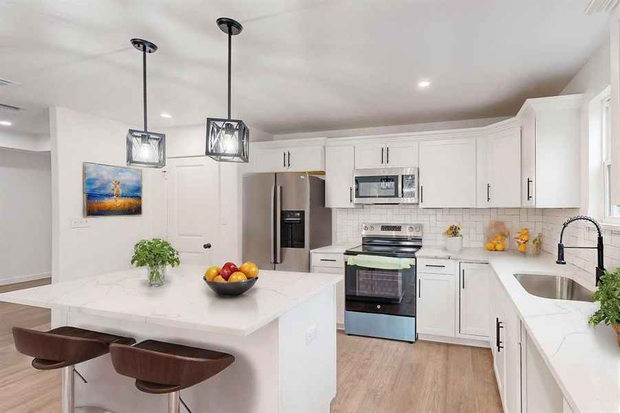 Kitchen featuring white cabinets, a kitchen island, sink, and stainless steel appliances