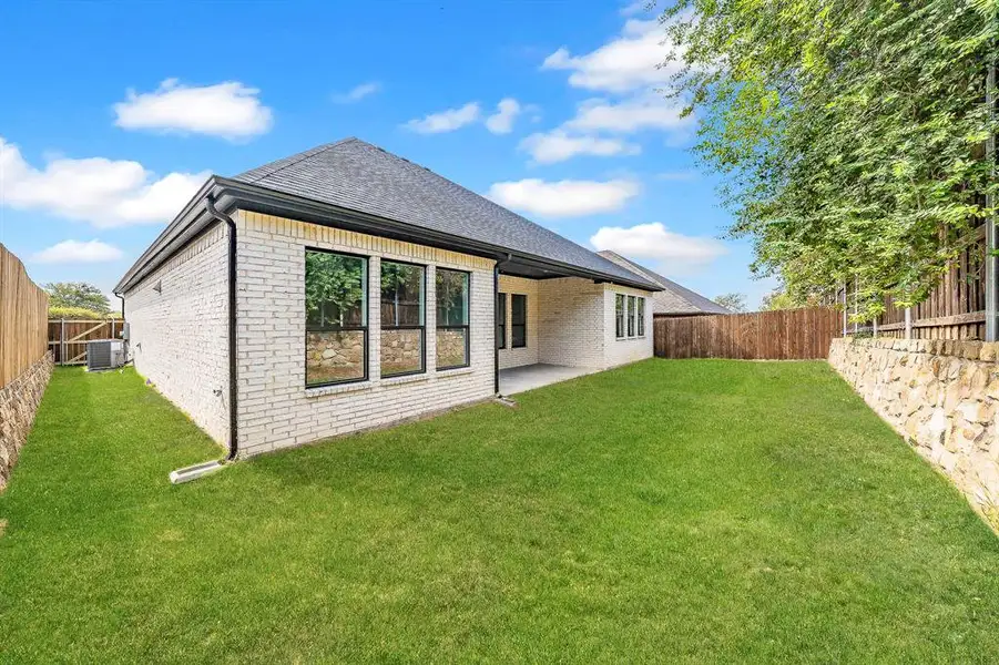 Rear view of house with brick siding, a patio area, a fenced backyard, and a shingled roof