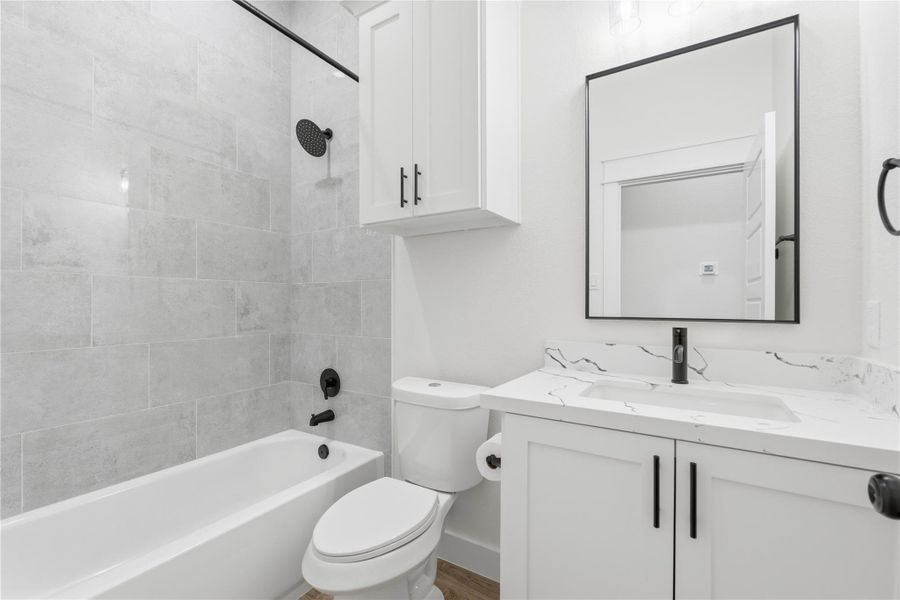 The second bathroom features generous storage, a shower-tub combination with a built-in soap niche, and sleek, modern fixtures.