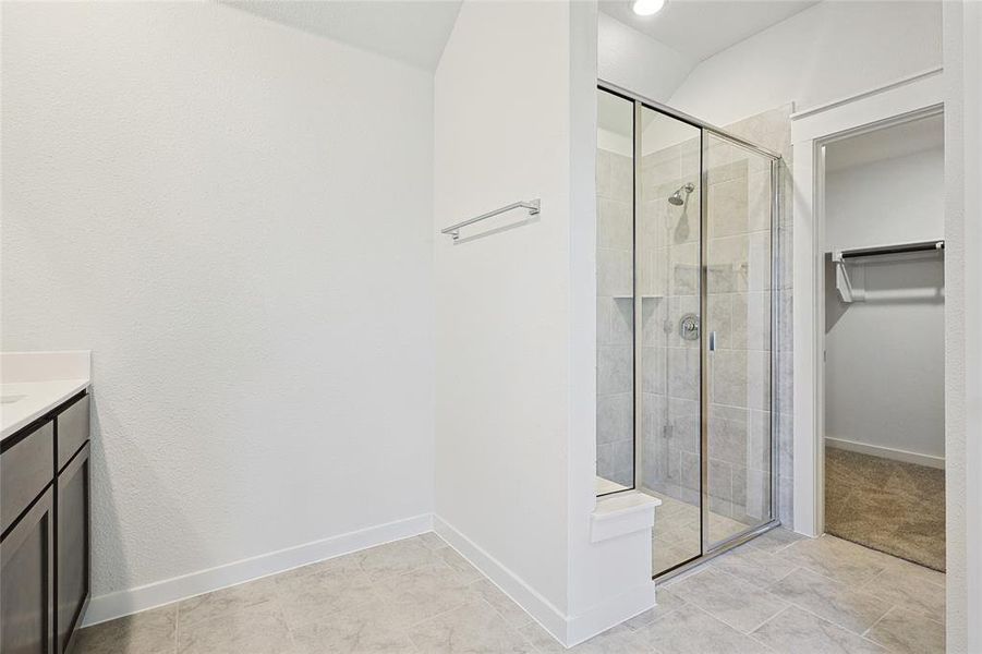 Bathroom featuring a shower with door, vanity, and tile patterned floors