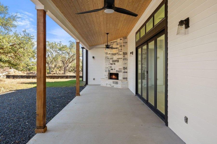 View of patio with ceiling fan and an outdoor stone fireplace