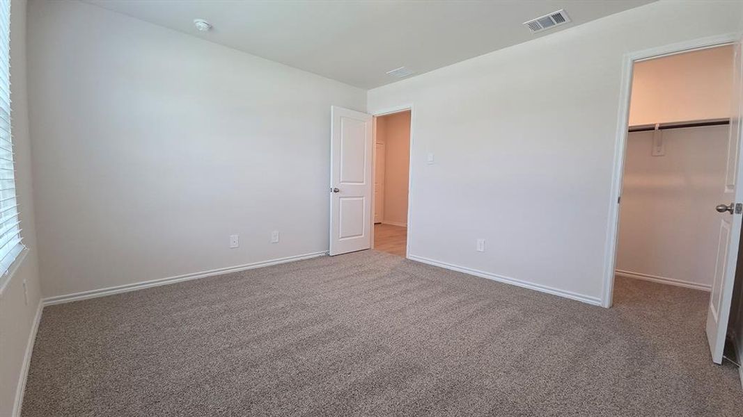 Carpeted interior space with white walls and baseboards Carpeted interior space with white walls and baseboards