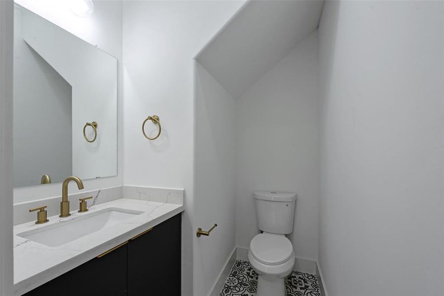 The half bath on the first floor is spacious. Beautiful brushed brass fixtures adorn the bath. The vanity boasts quartz counters and there is plenty of storage under the sink.