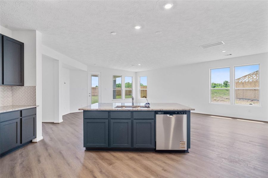 Additional view of the kitchen showcasing the beautiful granite island with a self-rimming single bowl kitchen sink with Moen faucet. The island also features an added breakfast bar.