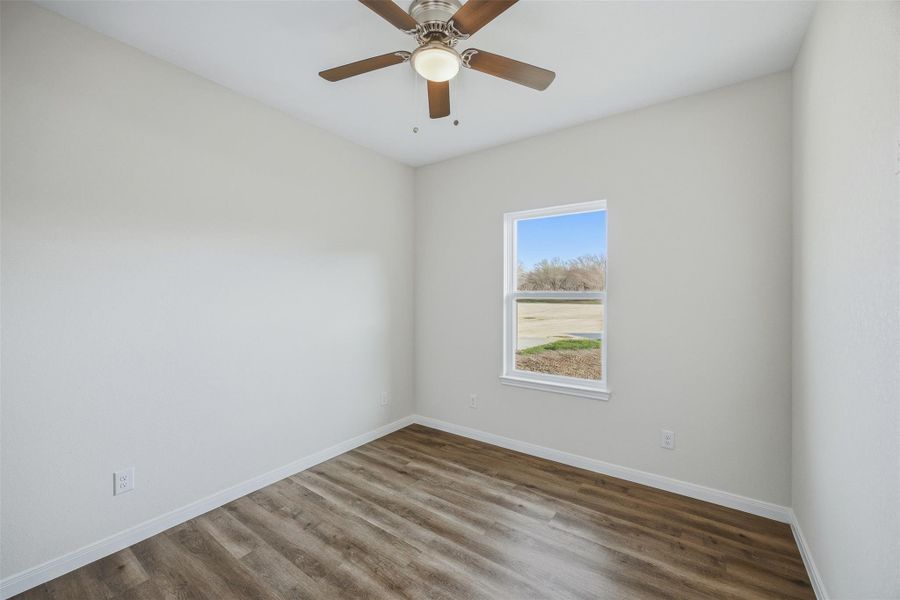 A quiet bedroom featuring elegant wood flooring and a refreshing ceiling fan.
