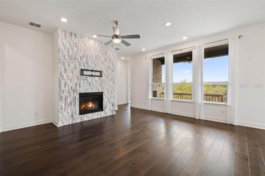 Unfurnished living room with a large fireplace, visible vents, wood finished floors, recessed lighting, and a ceiling fan