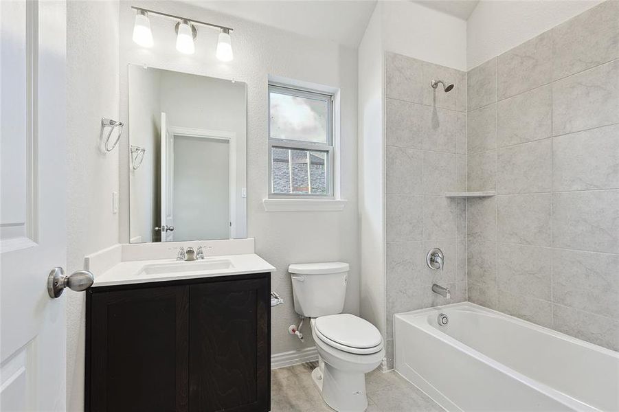 Full bathroom with vanity, tiled shower / bath, and toilet