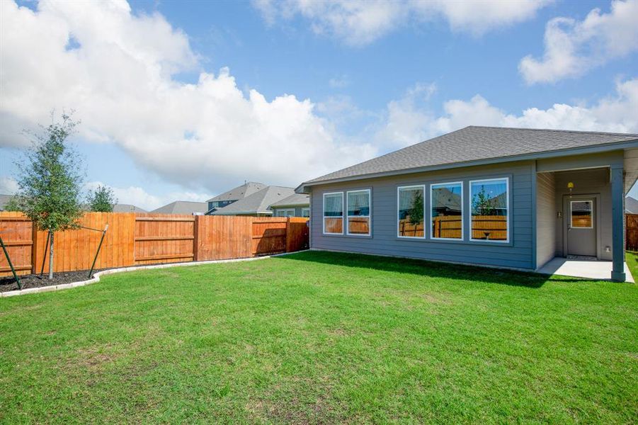 Step into your private oasis in the backyard, where lush landscaping and a covered patio create a serene atmosphere perfect for relaxation or entertaining guests.