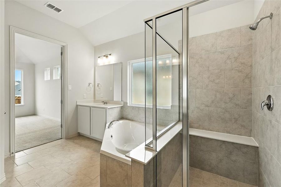 Full bathroom with a stall shower, a bath, vanity, lofted ceiling, and light tile patterned floors