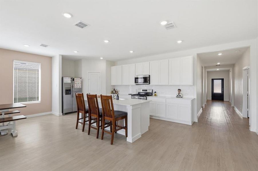 Contemporary kitchen featuring white cabinetry, a central island with countertop seating, stainless steel appliances, and recessed lighting Contemporary kitchen featuring white cabinetry, a central island with countertop seating, stainless steel appliances, and recessed lighting