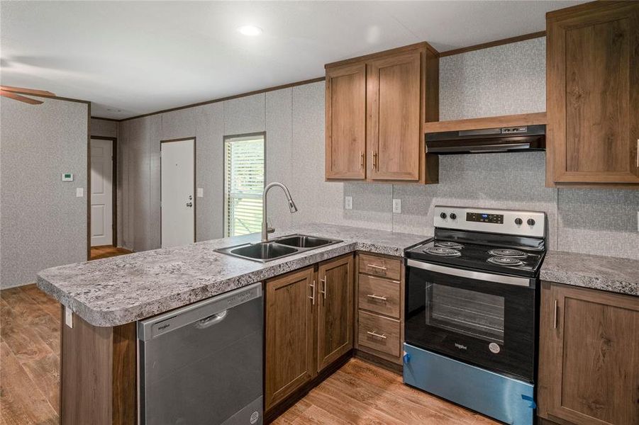 Kitchen with dishwasher, electric range, under cabinet range hood, a peninsula, and light wood-type flooring