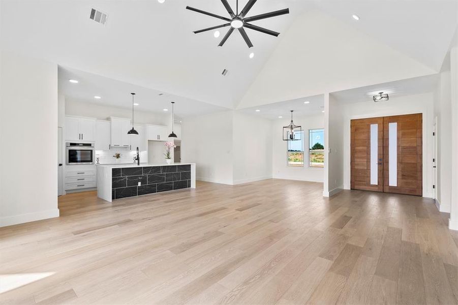 living room with high vaulted ceiling, a sink, recessed lighting, a ceiling fan, and a chandelier living room with high vaulted ceiling, a sink, recessed lighting, a ceiling fan, and a chandelier