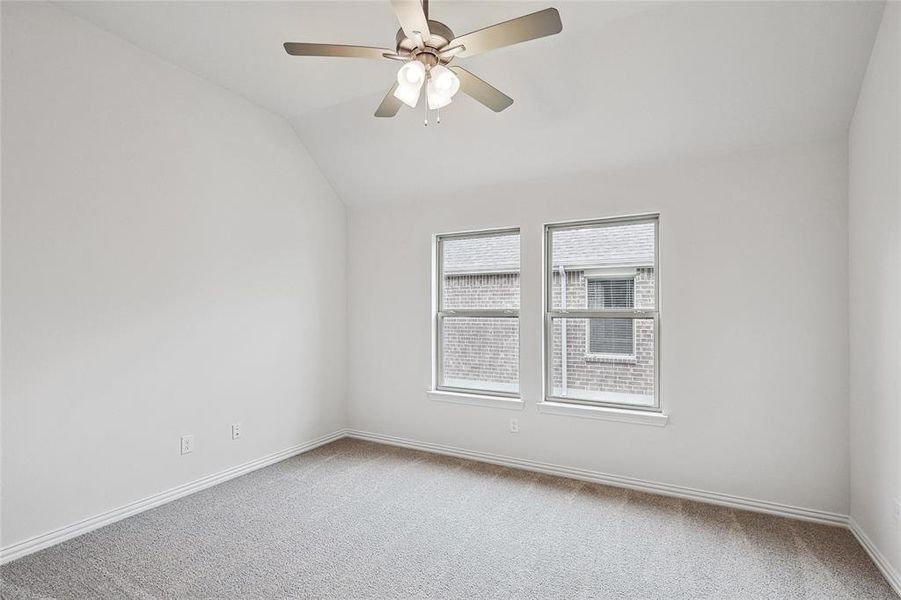 Carpeted spare room with ceiling fan and lofted ceiling