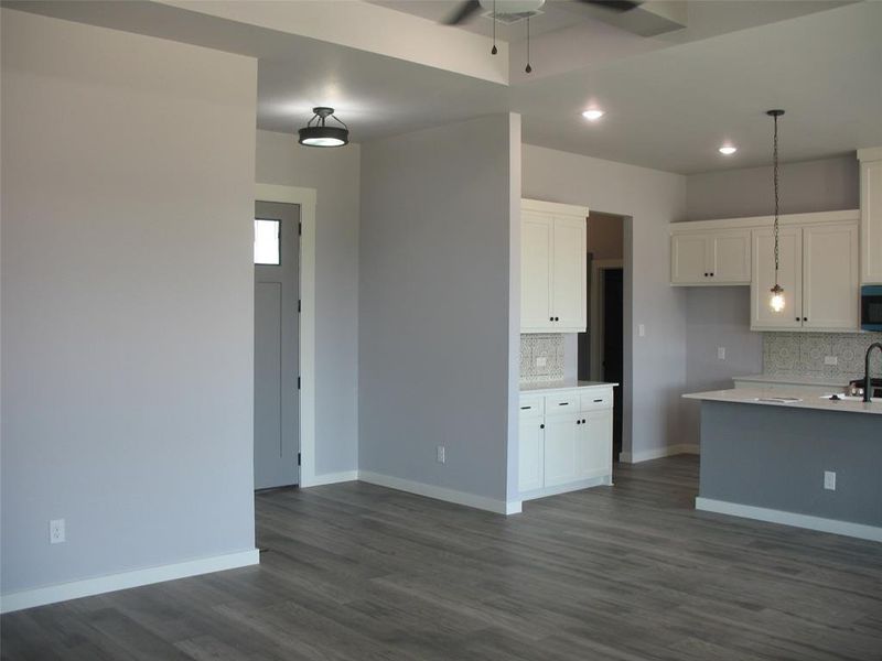 Kitchen featuring decorative light fixtures, dark wood finished floors, decorative backsplash, recessed lighting, and white cabinets