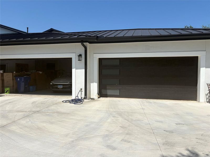 A well-maintained concrete driveway leads to the two-car garage with modern doors.