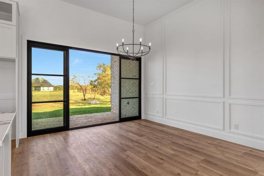 Dining area with a decorative wall, light wood-style floors, and a chandelier