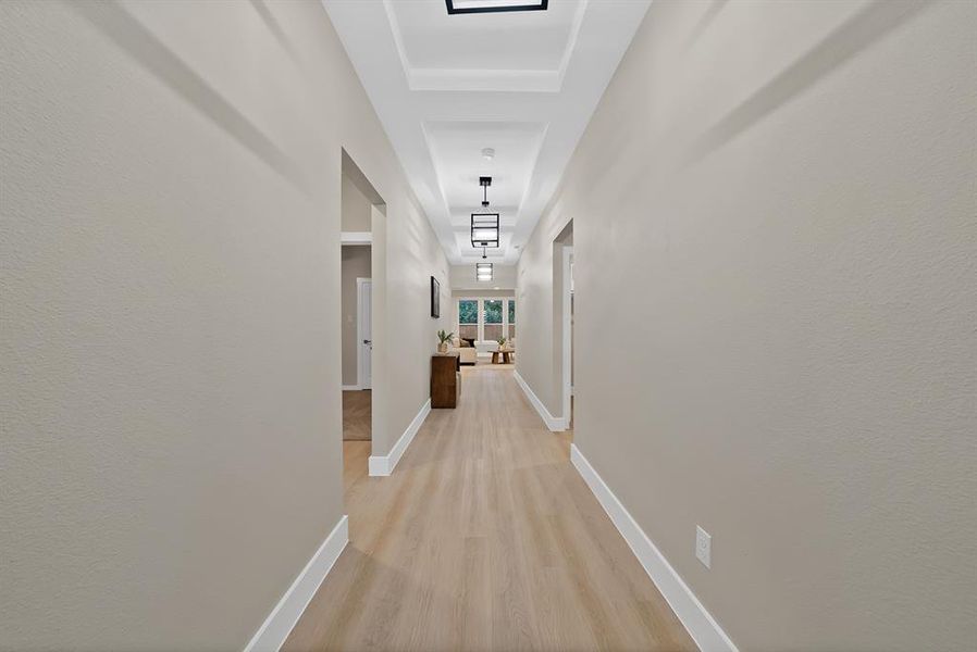 Hallway featuring light wood-finish flooring, neutral-toned walls, and recessed ceiling details Hallway featuring light wood-finish flooring, neutral-toned walls, and recessed ceiling details