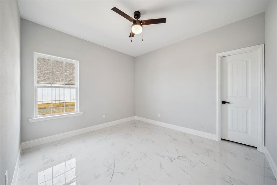 Room featuring large-format porcelain tile flooring, a multi-pane window, and a ceiling fan with integrated lighting