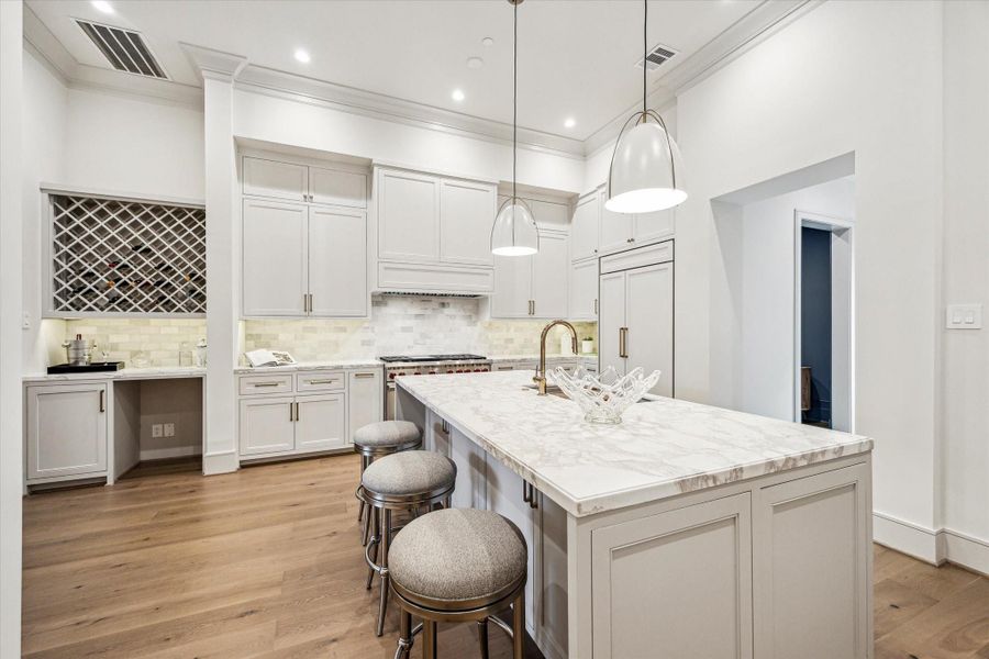 One side of the kitchen island features both storage and a counter for casual dining. Norman pendants light the island. At the back right is the walk-in pantry, and at the left is the custom-paneled Sub-Zero refrigerator freezer. The Wolf range features 2 ovens, six burners, and an infrared griddle. One side of the kitchen island features both storage and a counter for casual dining. Norman pendants light the island. At the back right is the walk-in pantry, and at the left is the custom-paneled Sub-Zero refrigerator freezer. The Wolf range features 2 ovens, six burners, and an infrared griddle.