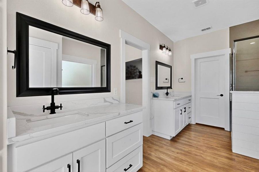 Bathroom featuring light wood finished floors and two vanities