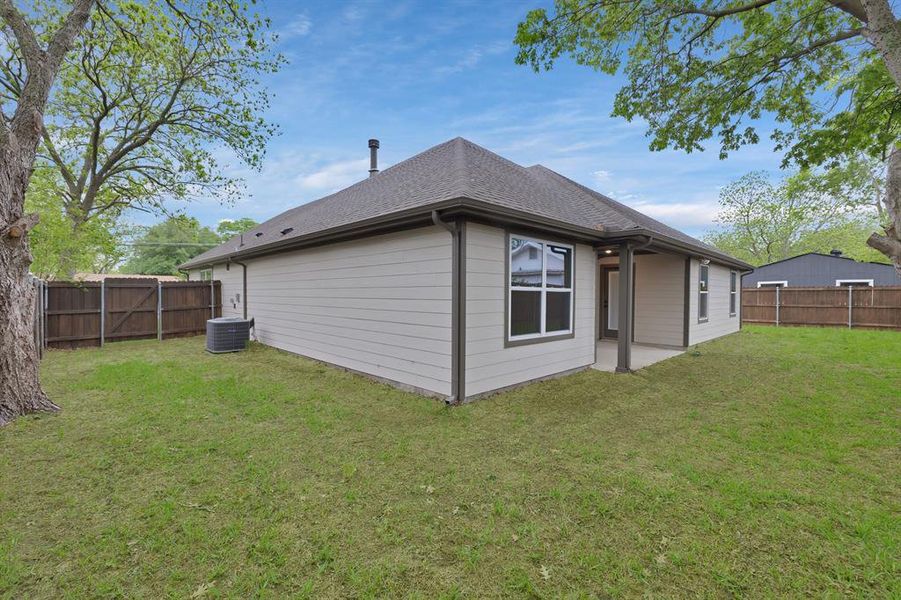 Rear view of property with a lawn, a shingled roof, a fenced backyard, and central AC unit Rear view of property with a lawn, a shingled roof, a fenced backyard, and central AC unit