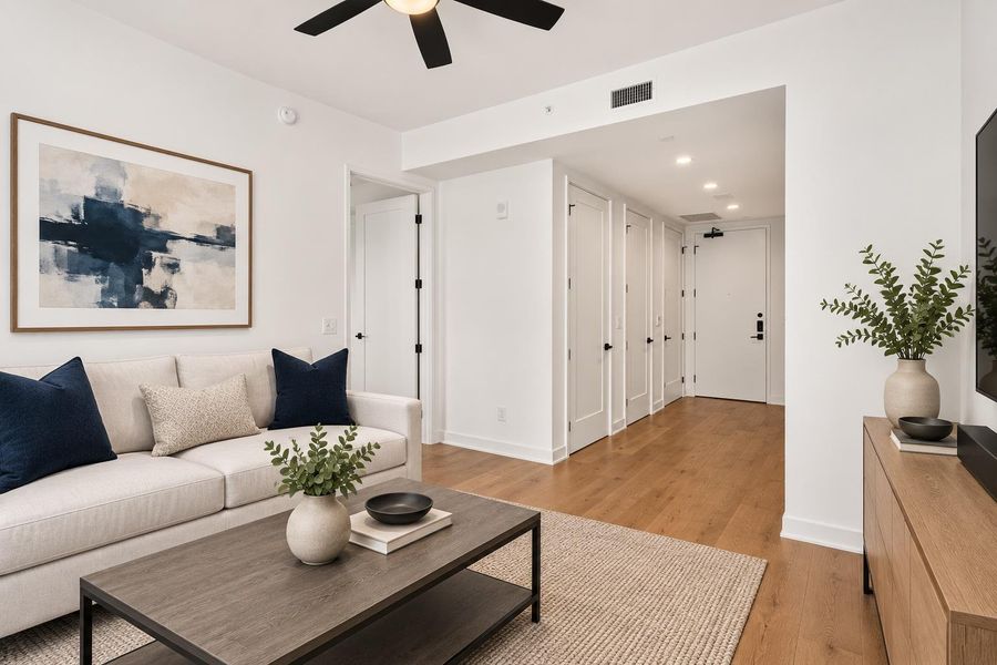 Bright hardwood floors lead through a well-designed living space with modern fixtures and ceiling fan.