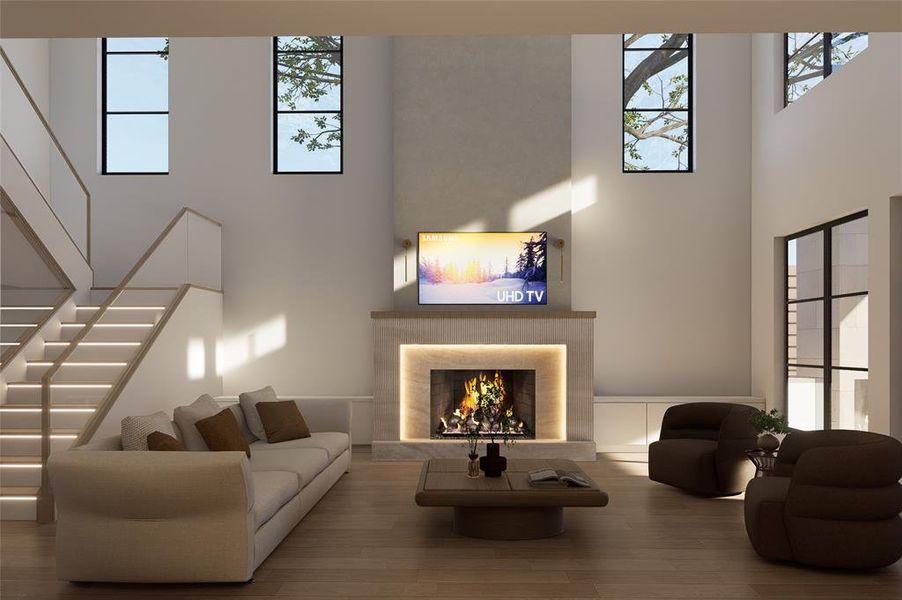 Living area featuring a warm lit fireplace, a high ceiling, wood finished floors, and healthy amount of natural light