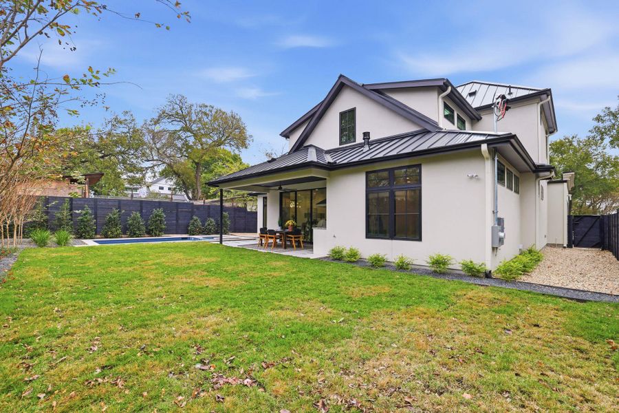 Back of property with a standing seam roof, a patio, a fenced backyard, and a metal roof