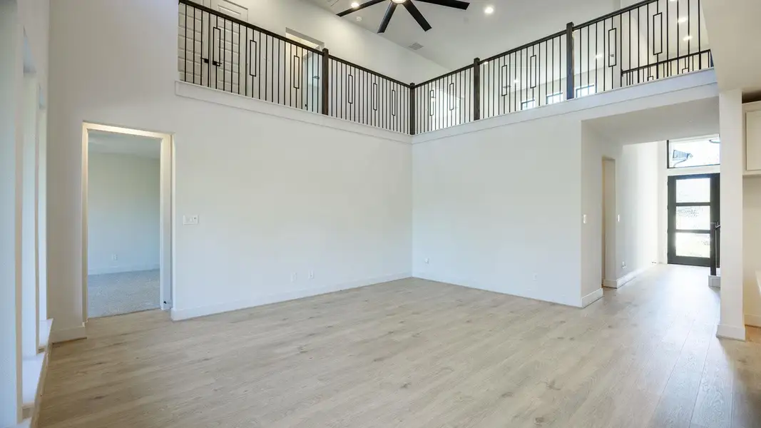 Unfurnished room featuring a towering ceiling and light wood-style flooring Unfurnished room featuring a towering ceiling and light wood-style flooring