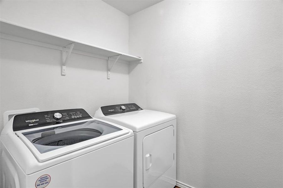 Laundry area featuring white textured walls, a built-in white shelving unit, and wood-finish flooring