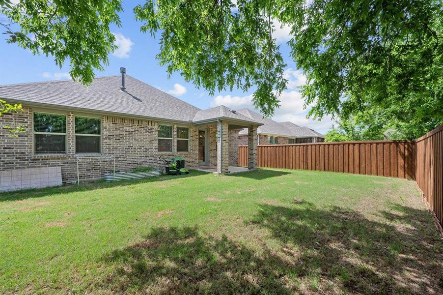 Expansive backyard featuring a manicured lawn, full privacy fencing, and a covered patio area Expansive backyard featuring a manicured lawn, full privacy fencing, and a covered patio area