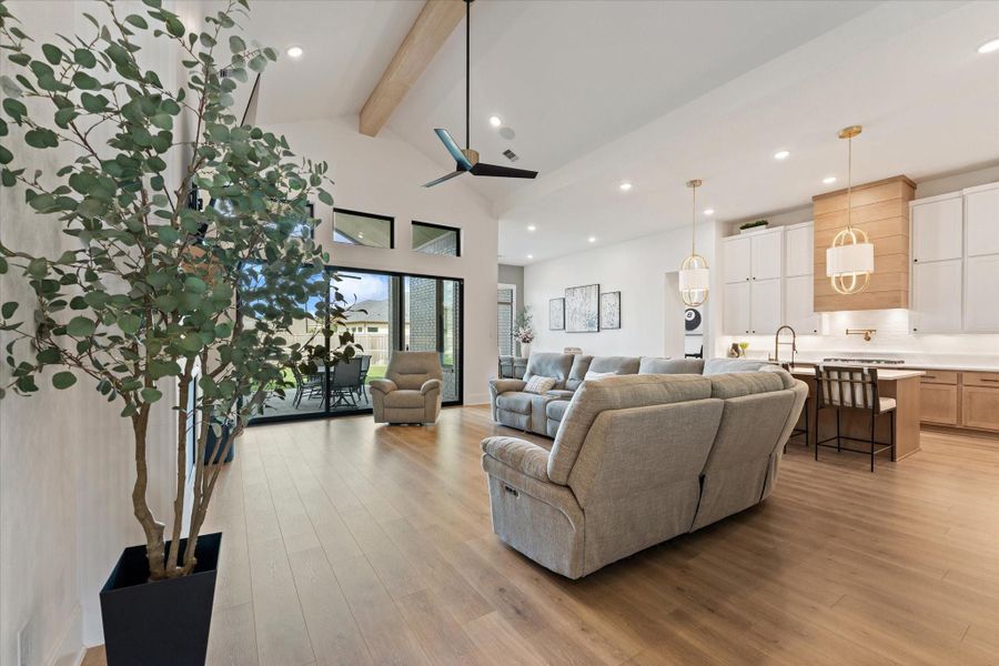 The open-concept living area showcases custom floating shelving, a striking modern fireplace, and beautiful wood-look flooring that adds warmth and elegance to the space.