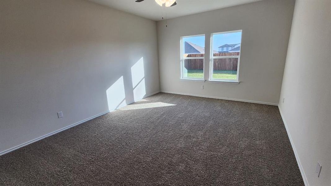 Spacious interior room with neutral-toned walls, plush carpeting, and a ceiling fan Spacious interior room with neutral-toned walls, plush carpeting, and a ceiling fan
