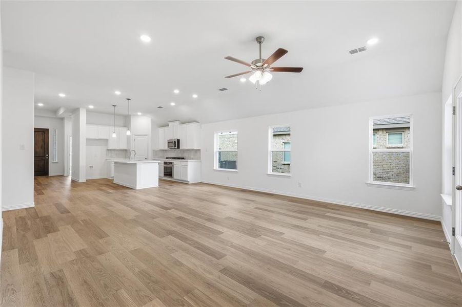 Open-concept living area with light wood-finish flooring, recessed lighting, and a ceiling fan